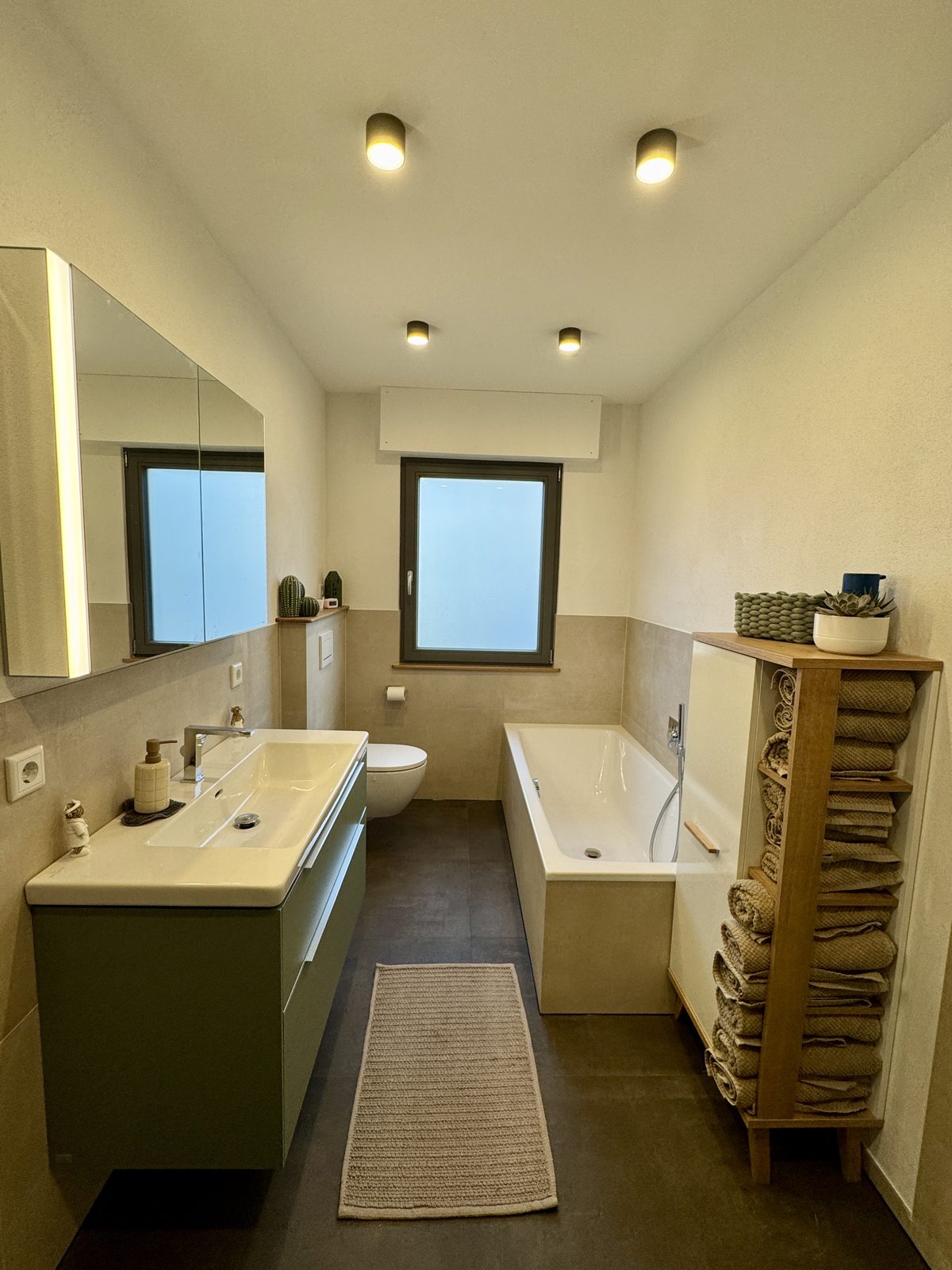 Modernes Bad mit Waschtisch, Wand-WC und Badewanne in beigen Fliesen